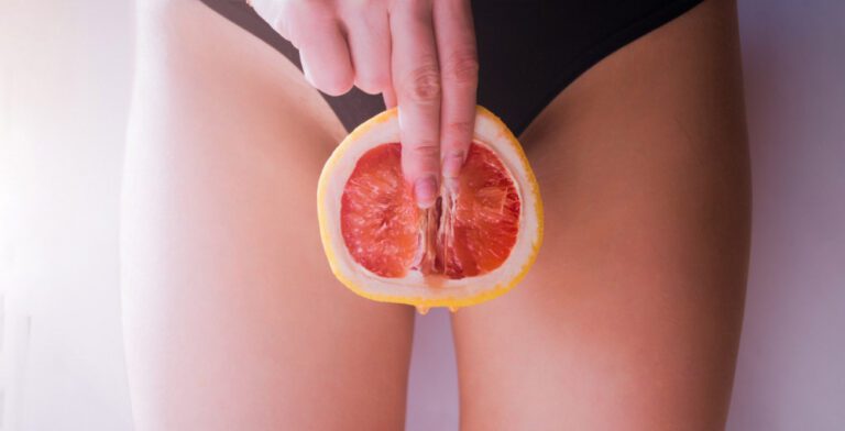 A woman in a bikini holding a grapefruit.